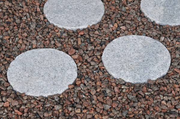 Granit Trittstein grau geflammt 30 x 30 x 3 cm in rot braunem Kies verlegt