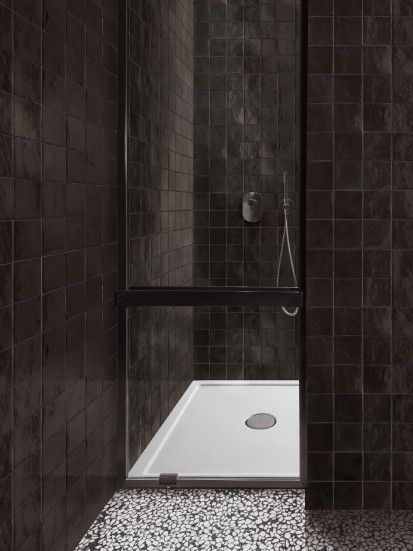 Begehbare Dusche mit weisser Duschtasse und dunkler Wand