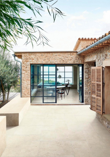 Terrassenplatten mediterran in beige mit Blick auf schwarze Wohnzimmerfenster