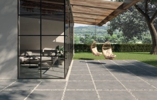 Terrassenplatten grau modern mit breiten Fugen und Wiese mit Bäumen im Hintergrund