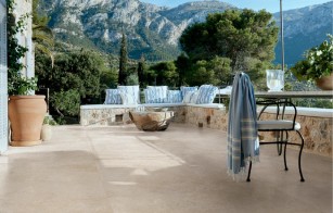 Beige Terrassenplatten im mediterranen Stil mit Stuhl und Bergen sowie Bäumen im Hintergrund