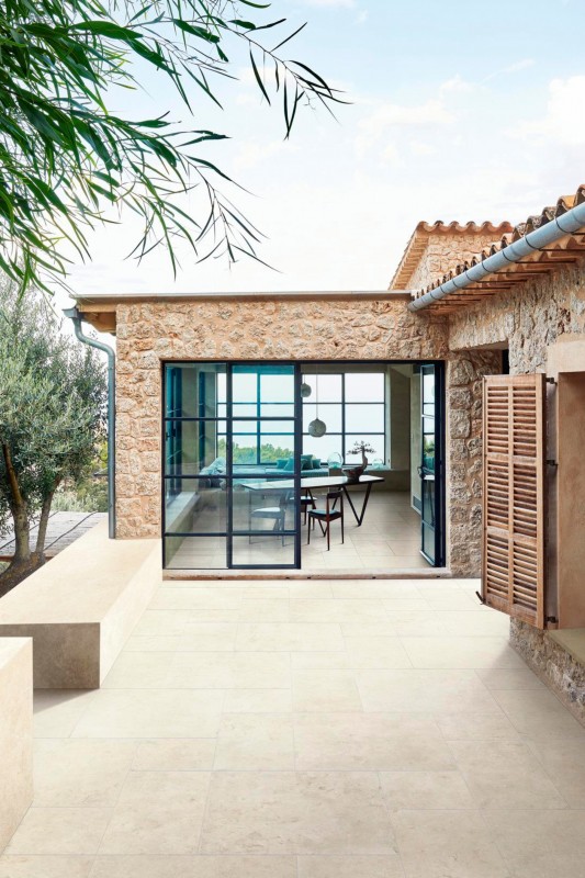 Terrassenplatten mediterran in beige mit Blick auf schwarze Wohnzimmerfenster